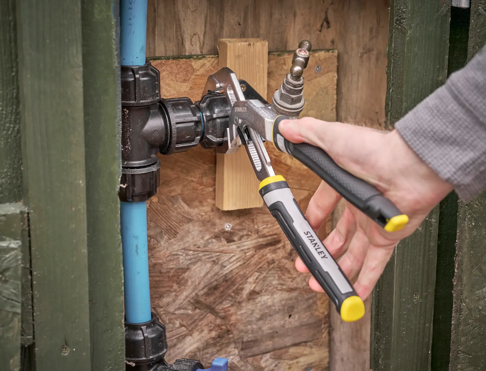 Photo of STANLEY FMHT75512-0 adjustable pliers used on a plumbing fitting, close-up during installation.