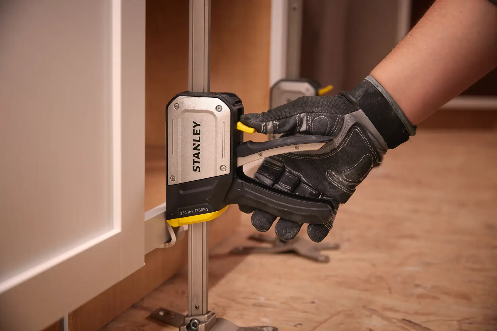 STANLEY FMHT83550-1 Schrankzwinge im Einsatz, Nahaufnahme, schwarzes und silbernes Werkzeug mit gelbem Hebel.
