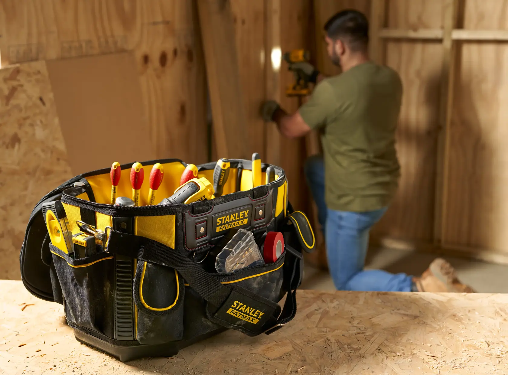 STANLEY FMST1-70749 tool bag in black and yellow, filled with hand tools, photographed on a workbench.