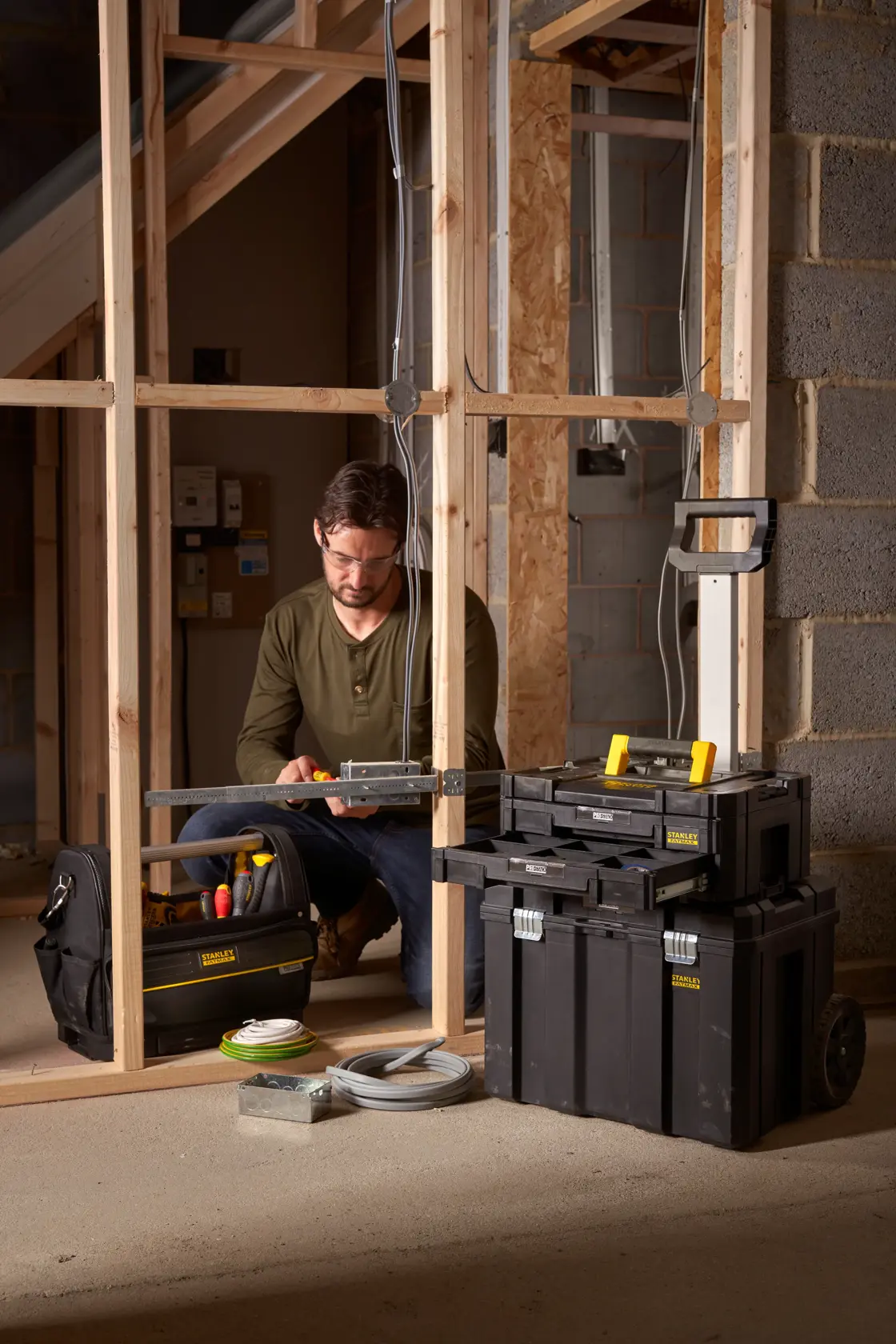 STANLEY FMST1-71969 mobile tool chest on wheels with top handle, shown at a construction site.