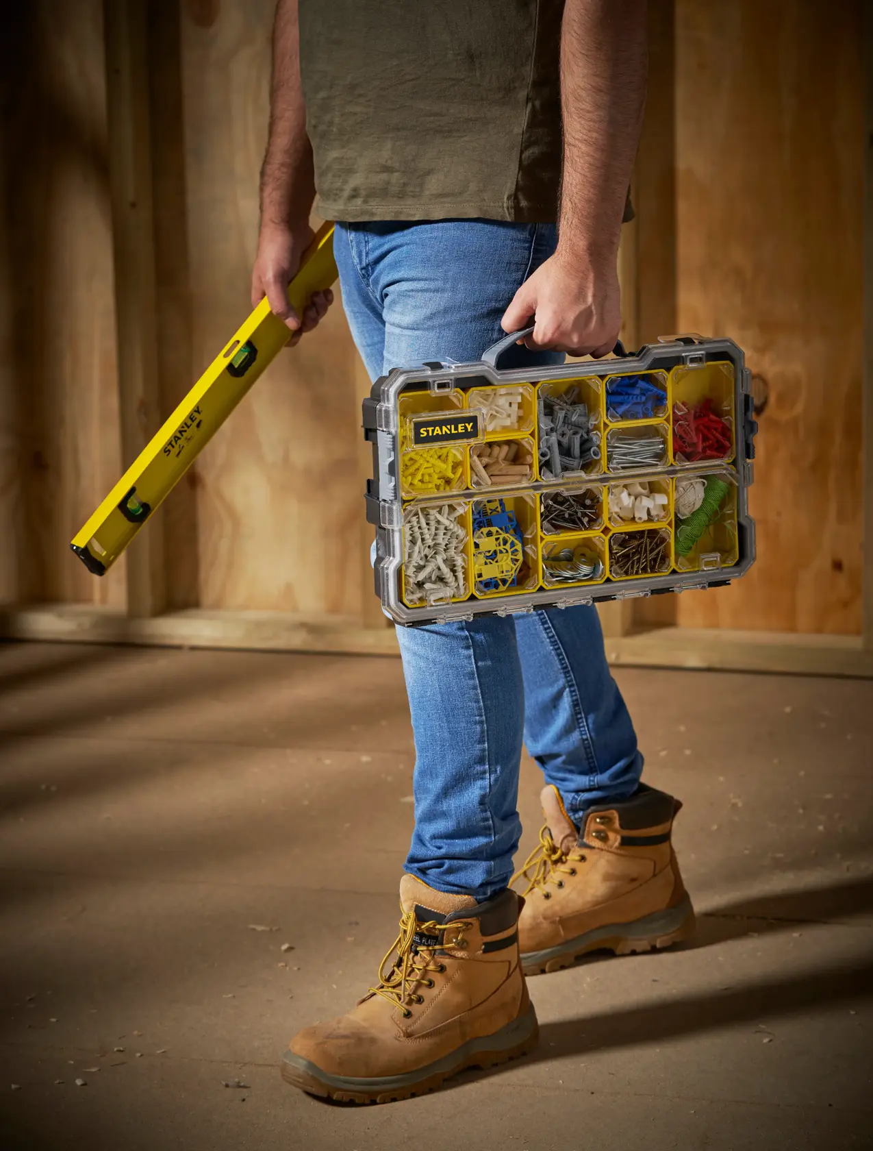 STANLEY FMST1-75779 organiser box with compartments, held by person, side angle, construction site.