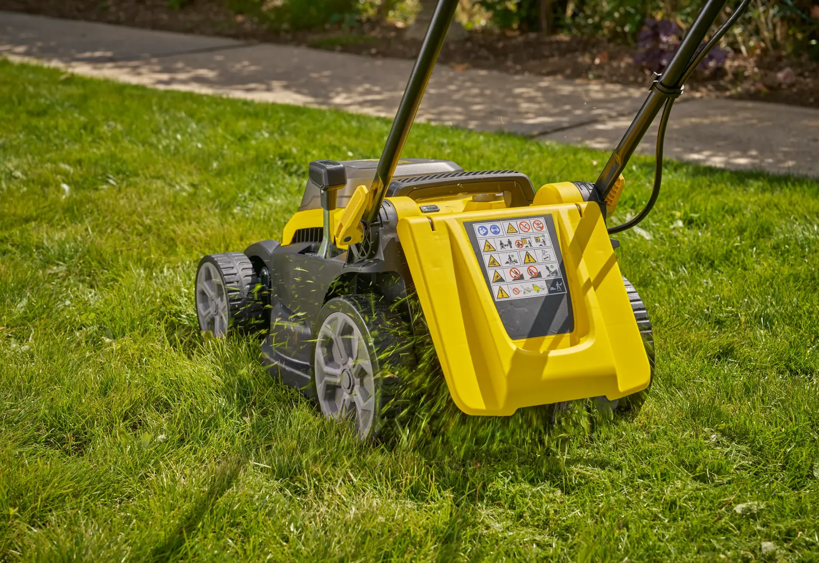 STANLEY SCMWP3401M1-XE Rasenmäher in Gelb und Schwarz schneidet Gras, Rückansicht, im Freien.