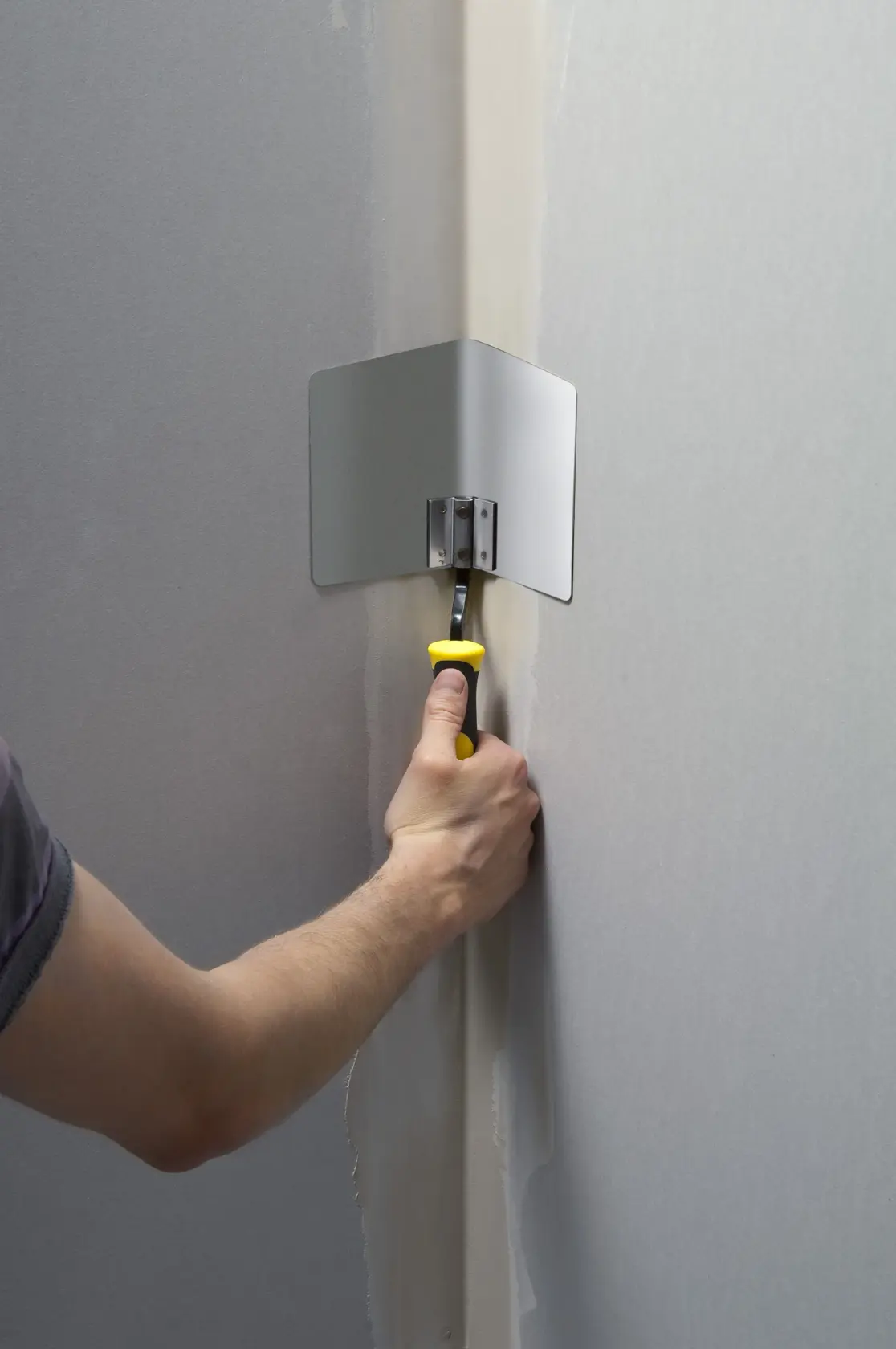 STANLEY STHT0-05777 Eckenspachtel mit gelbem Griff zum Glätten von Spachtelmasse in einer Wandecke.