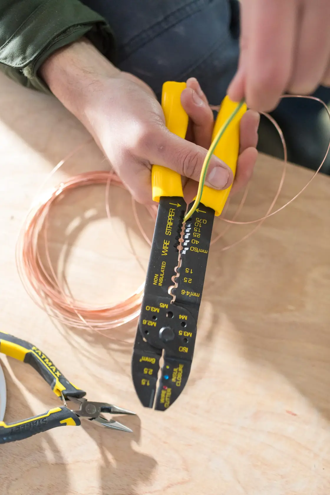 Photo of STANLEY STHT0-75414 wire stripper with yellow handles being used to strip wire, side view.