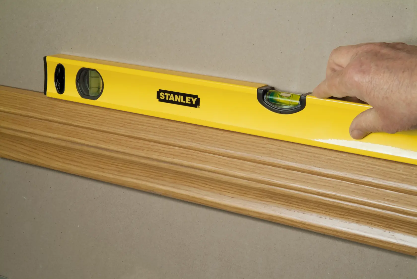 STANLEY STHT1-43103 spirit level checking alignment on wood trim, close-up side angle.