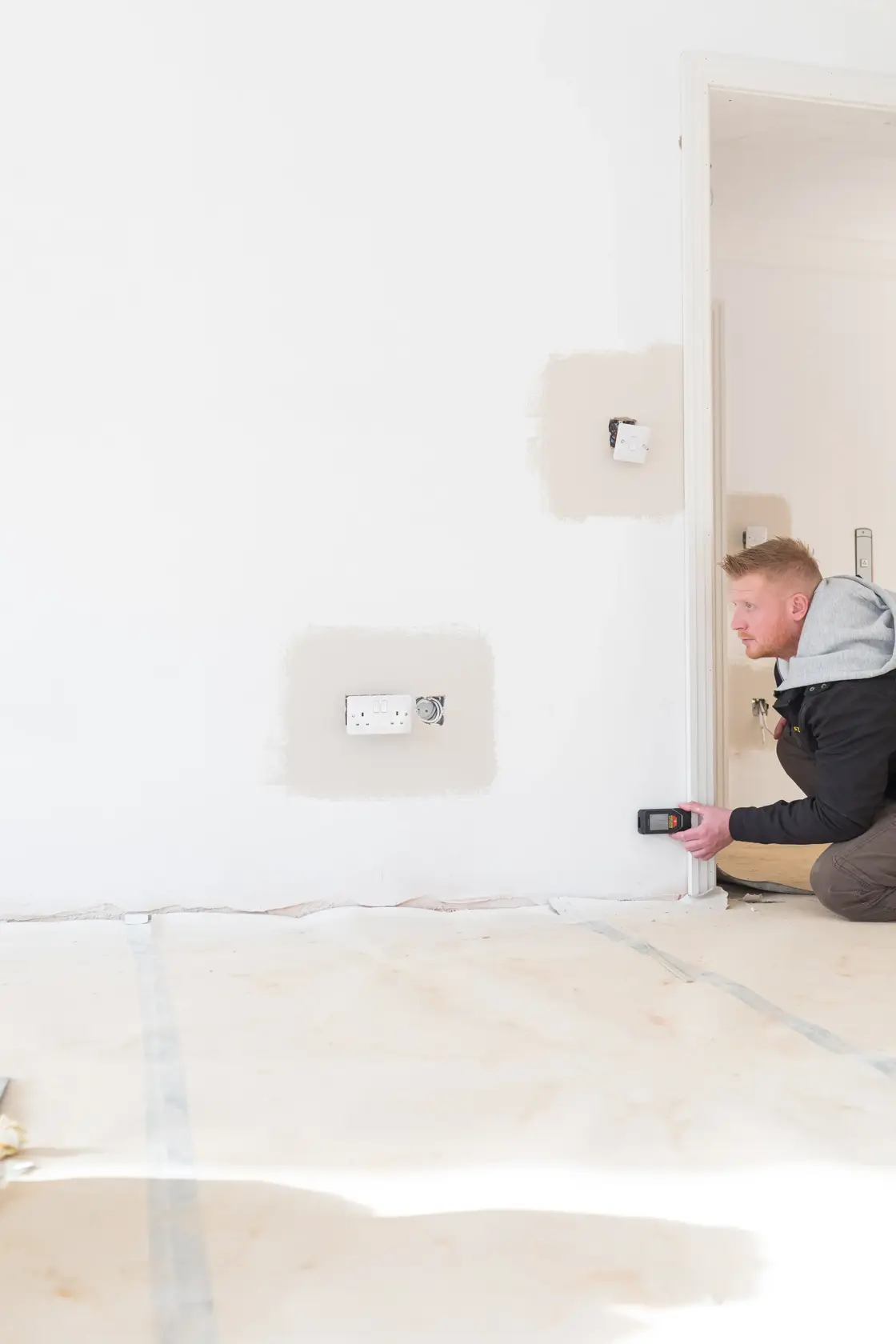 Photo of STANLEY STHT1-77142 wall scanner in use, person scanning white wall near electrical outlet.