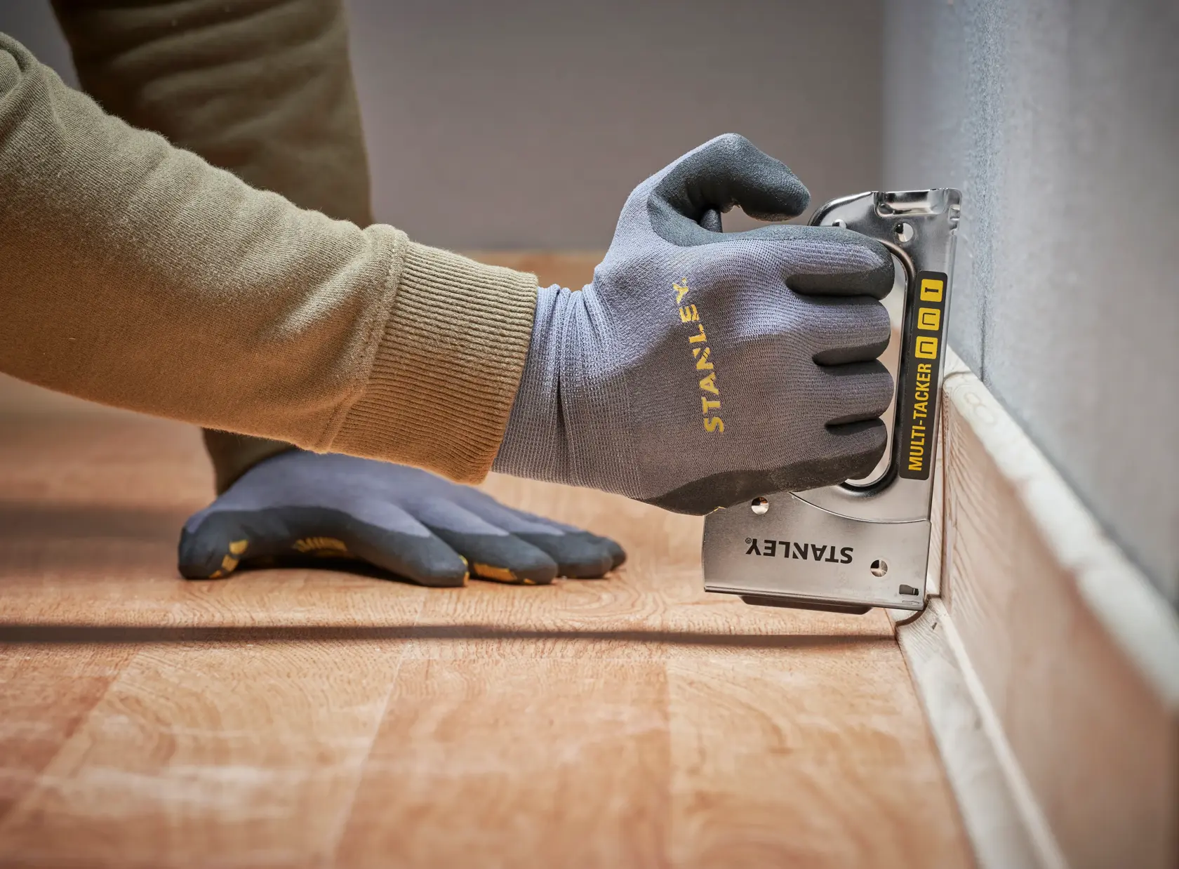 STANLEY STHT6-70410 Multi-Tacker am Bodenleisten, Nahaufnahme, Handschuhe sichtbar.
